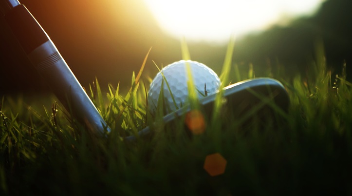 golf club and golf ball close up in grass field with sunset.